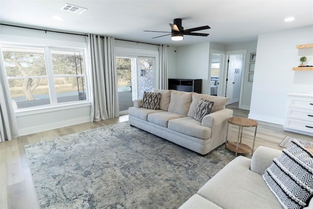 living room featuring light wood-style flooring, recessed lighting, a ceiling fan, visible vents, and baseboards