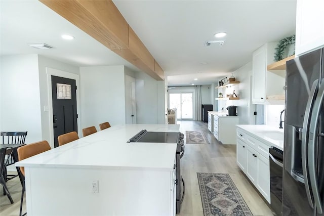 kitchen featuring a kitchen island, refrigerator with ice dispenser, a kitchen bar, and open shelves