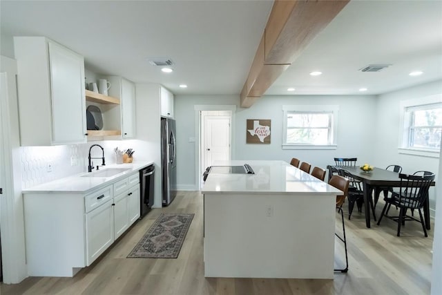 kitchen featuring dishwashing machine, a sink, white cabinetry, light countertops, and open shelves