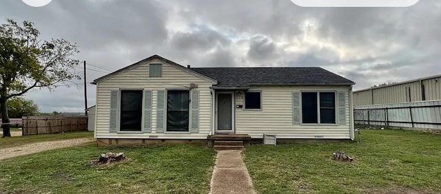 view of front of property featuring entry steps, fence, and a front lawn