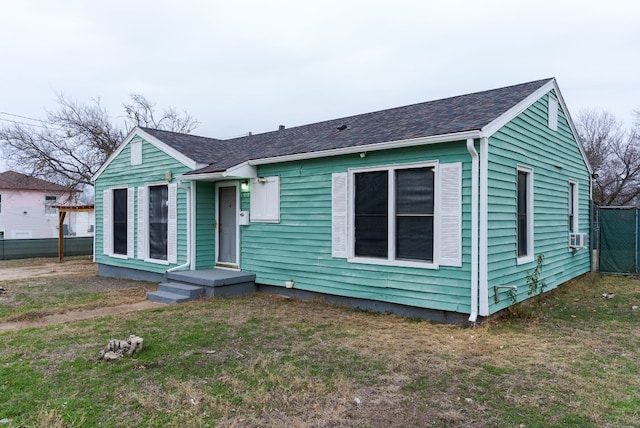 view of front of property featuring fence, a front lawn, cooling unit, and roof with shingles