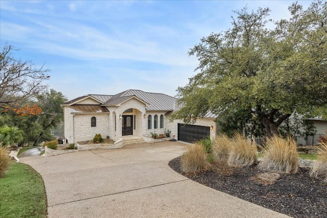 view of front of property featuring concrete driveway, a standing seam roof, metal roof, a garage, and stone siding