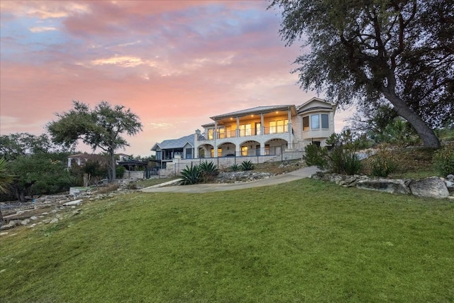 17813 Kingfisher Ridge Dr, Lago Vista, TX 78645 - back of house at dusk with a balcony, a lawn, and a porch