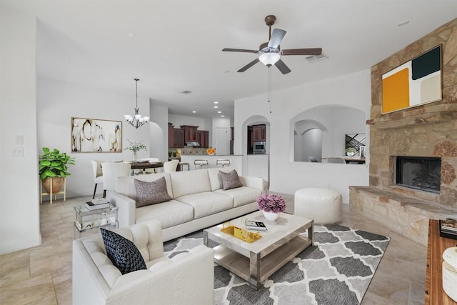 living area featuring ceiling fan with notable chandelier, a stone fireplace, visible vents, and recessed lighting