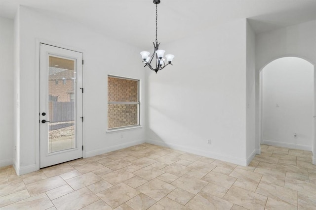 unfurnished room featuring baseboards, arched walkways, and a chandelier