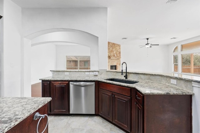 kitchen featuring dishwasher, ceiling fan, light stone countertops, dark brown cabinets, and a sink