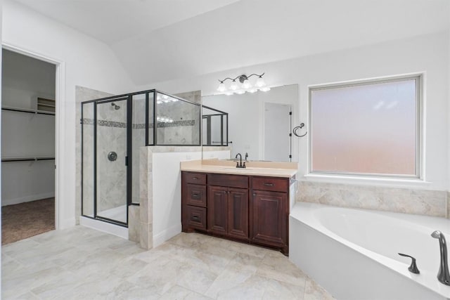 bathroom with vanity, vaulted ceiling, a shower stall, a bath, and a walk in closet