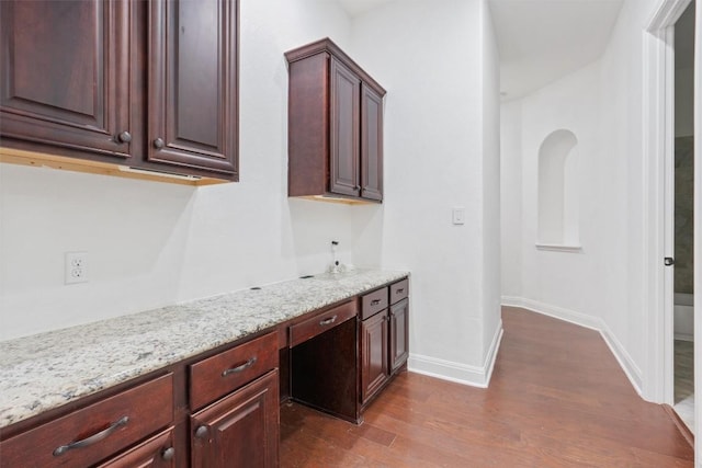 kitchen featuring baseboards, light stone counters, and dark wood finished floors