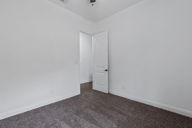 empty room featuring a ceiling fan, dark colored carpet, and baseboards