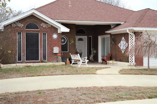 view of front of house with brick siding and a shingled roof