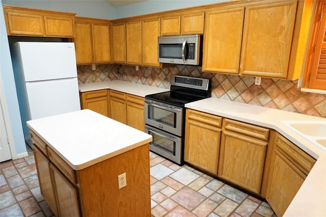 kitchen with brown cabinets, decorative backsplash, stainless steel appliances, and light countertops