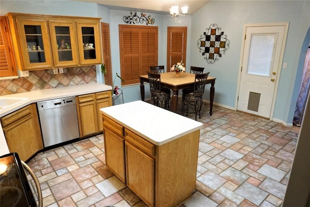 kitchen featuring pendant lighting, brown cabinets, light countertops, stainless steel dishwasher, and glass insert cabinets