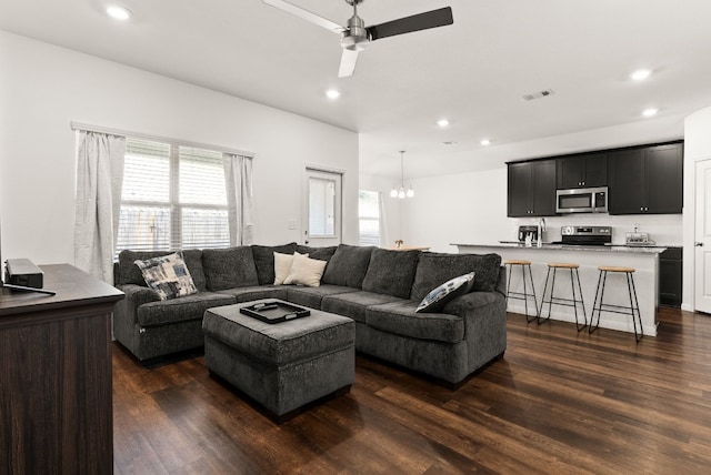 living room with ceiling fan with notable chandelier, visible vents, dark wood-type flooring, and recessed lighting