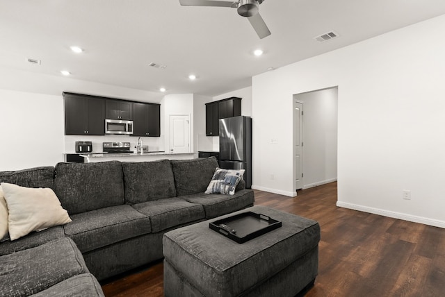 living room with baseboards, visible vents, dark wood-type flooring, and recessed lighting