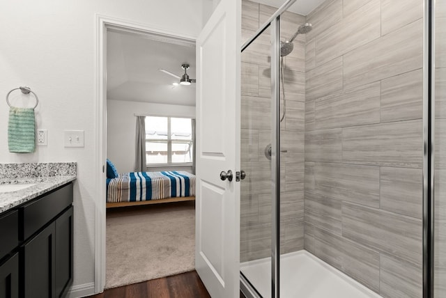 ensuite bathroom with ensuite bathroom, a stall shower, ceiling fan, vanity, and wood finished floors