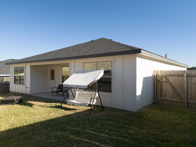 back of property with a patio, fence, board and batten siding, and a yard