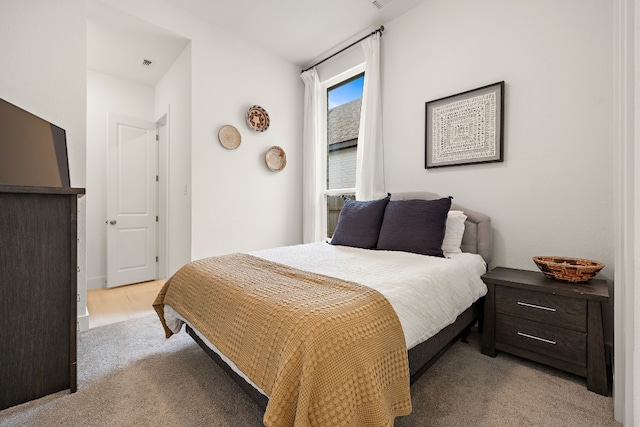bedroom featuring visible vents and light colored carpet