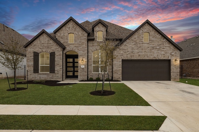french country style house featuring brick siding, a front yard, fence, and concrete driveway