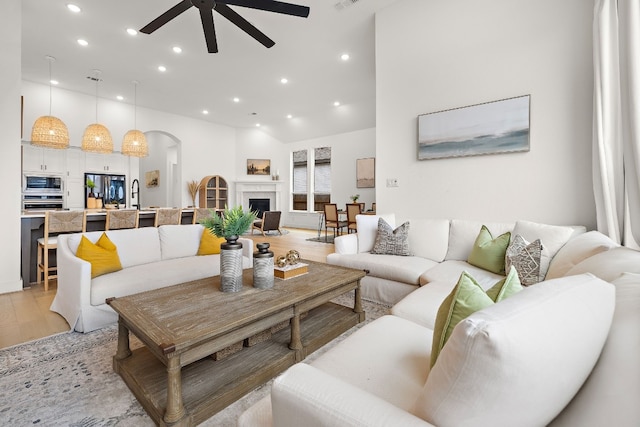 living area with visible vents, arched walkways, ceiling fan, recessed lighting, and light wood-style flooring