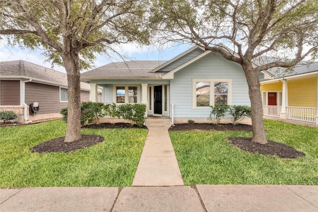 ranch-style home with a front lawn and roof with shingles