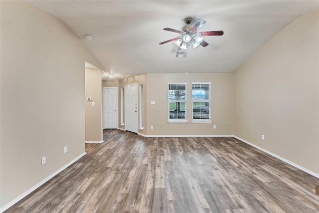 empty room featuring lofted ceiling, visible vents, dark wood finished floors, and baseboards