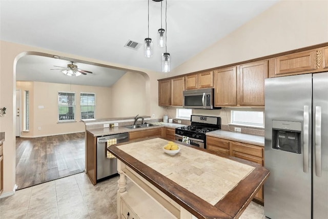 kitchen with arched walkways, visible vents, hanging light fixtures, appliances with stainless steel finishes, and a sink