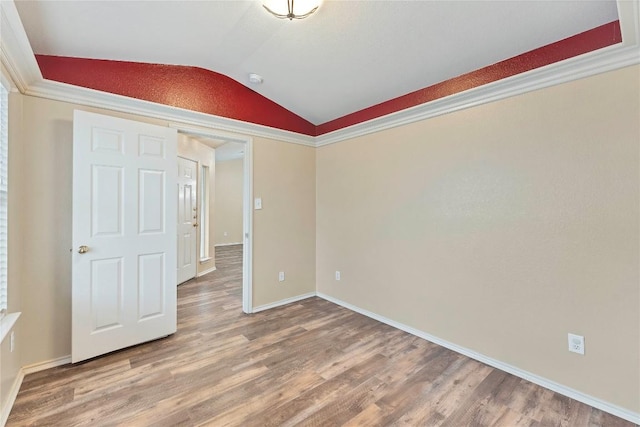 unfurnished room with lofted ceiling, baseboards, and wood finished floors