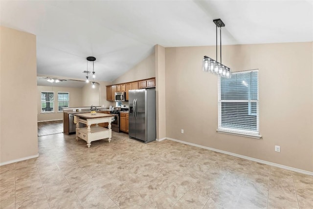 kitchen with an island with sink, appliances with stainless steel finishes, brown cabinets, and hanging light fixtures