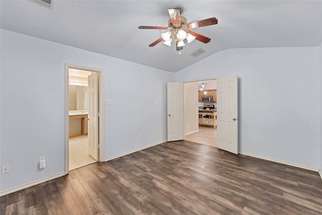 unfurnished bedroom featuring dark wood-type flooring, visible vents, baseboards, vaulted ceiling, and ensuite bath