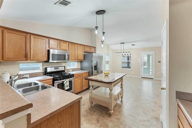 kitchen featuring visible vents, a kitchen island, hanging light fixtures, stainless steel appliances, and a sink