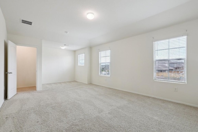 spare room featuring visible vents, light carpet, and baseboards