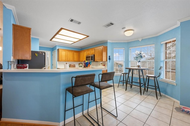 kitchen featuring a peninsula, appliances with stainless steel finishes, visible vents, and light countertops