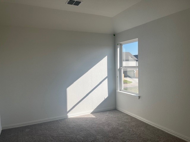 carpeted spare room featuring baseboards and visible vents