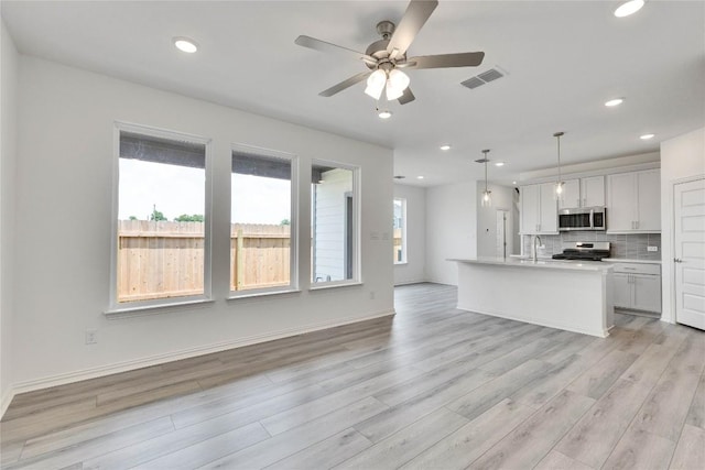 522 Ansley Ct, Taylor, TX 76574 - kitchen with stainless steel microwave, range, light wood-type flooring, a ceiling fan, and backsplash