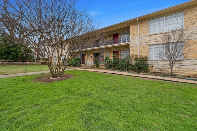 view of front of home featuring a front lawn, a balcony, and brick siding