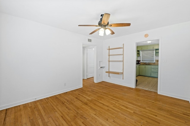 interior space featuring light wood-style flooring, visible vents, baseboards, and ensuite bathroom