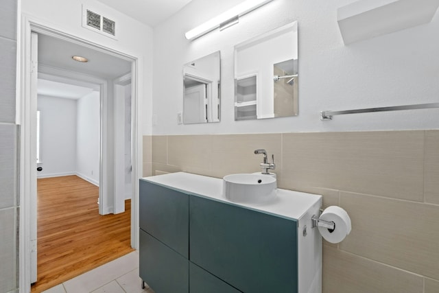 bathroom with visible vents, a wainscoted wall, tile patterned flooring, vanity, and tile walls