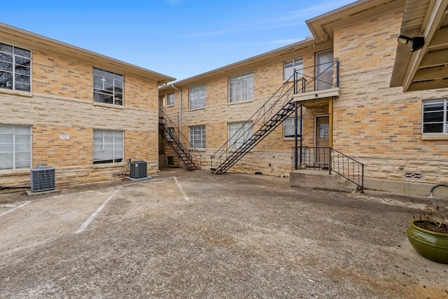 exterior space with stone siding, central AC, brick siding, and stairway