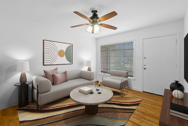 living area featuring ceiling fan, baseboards, and wood finished floors