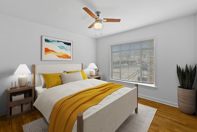 bedroom featuring a ceiling fan, baseboards, and wood finished floors