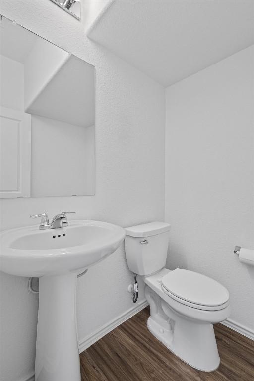 bathroom with a sink, wood finished floors, toilet, and baseboards