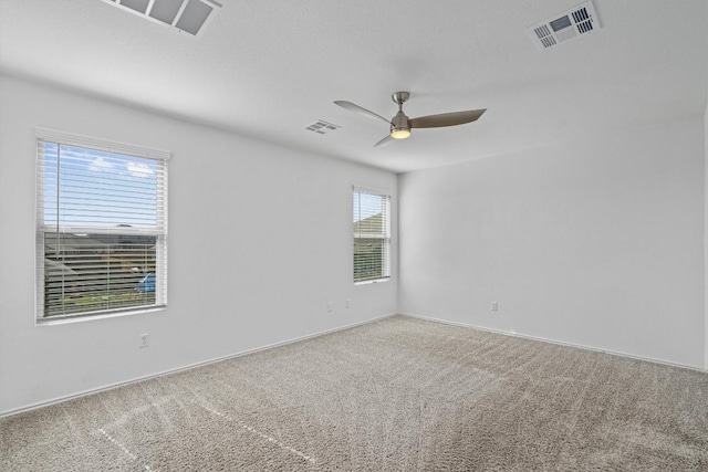 spare room featuring carpet floors, ceiling fan, and visible vents