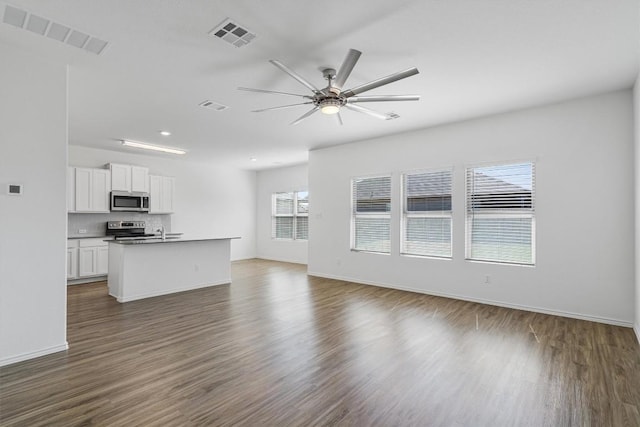 unfurnished living room with visible vents, dark wood-style flooring, and a ceiling fan