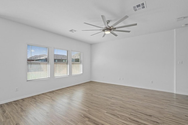 empty room featuring visible vents, ceiling fan, baseboards, and wood finished floors