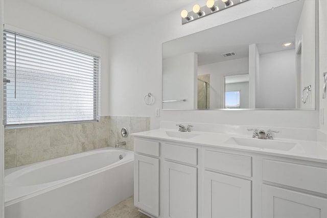 bathroom with double vanity, visible vents, a sink, and a bath