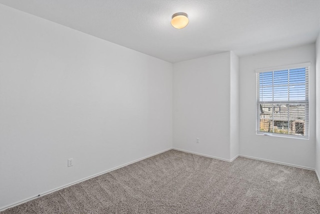 carpeted spare room featuring baseboards