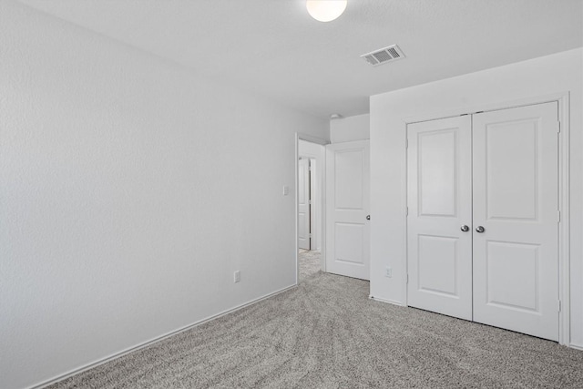 unfurnished bedroom featuring visible vents, a closet, and light colored carpet