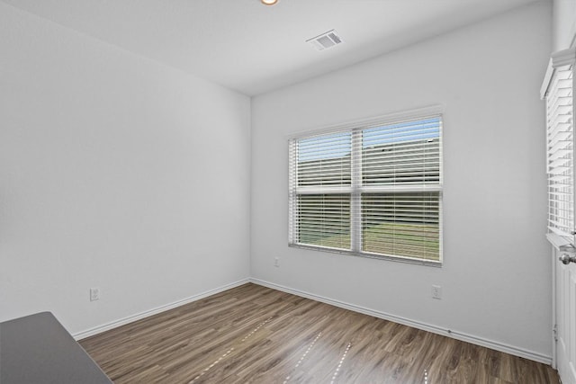 unfurnished room with baseboards, visible vents, and wood finished floors