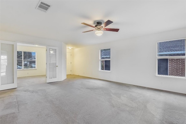 unfurnished room featuring a ceiling fan, light colored carpet, french doors, and visible vents