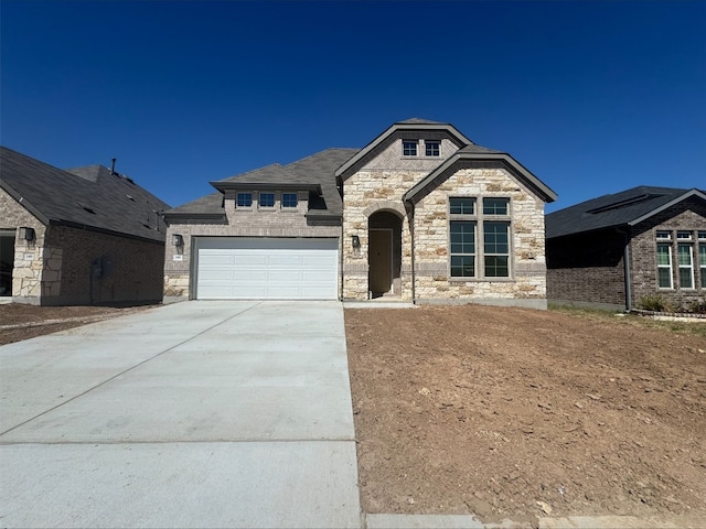 french country inspired facade featuring concrete driveway and a garage